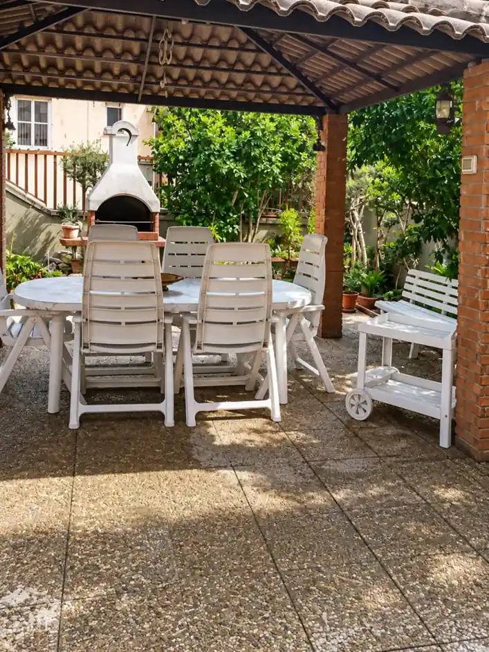 Gazebo coperto con tavolo da pranzo e barbecue in muratura in giardino